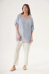 Blusa celeste de lino, corte holgado, cuello redondo y mangas 3/4 con botón.
