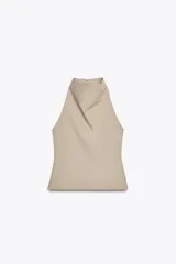 Top color beige de cuello halter con botones y espalda descubierta. Cierre lateral con cremallera oculta.