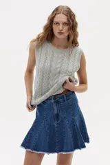 Chaleco tejido gris melange con diseño de ochos, cuello redondo y sisas amplias. Confeccionado en algodón y acrílico.