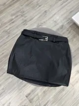 Minifalda negra de cuero sintético con cinturón con hebilla metálica.