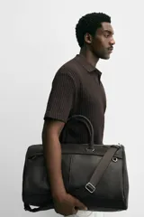 Bolso de viaje negro con acabado grabado, compartimento principal con cierre de cremallera, bolsillo interior con cierre de cremallera, bolsillo frontal con cierre de cremallera, asa de hombro removible y ajustable.