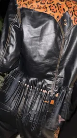 Campera corta de cuero negro, estilo torera, con animal print y flecos en la espalda.