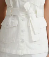 Chaleco blanco en sarga con cuello solapa, cierre en botones, martingale en el hombro, cuatro bolsillos delanteros con solapa, cintura con transeúntes anchos y cinturón con pespuntes para amarre.