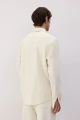 Camisa color crema en mezcla de lino y algodón, de corte regular fit, manga larga con puños abotonados, cuello inglés, tapeta clásica, canesú en la espalda, bolsillo superior abierto y bajo redondeado.