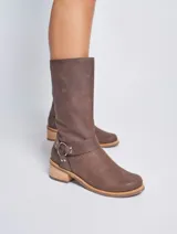 Bota de cuero color marrón con caña media, taco de madera y detalle de arnés con aro metálico.