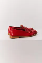 Mocasín de cuero color marrón claro, con detalle de flecos y borlas en la parte delantera. Diseñado en Uruguay y fabricado en Brasil.