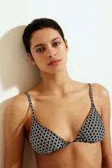 Top de bikini triangular con estampado geométrico en blanco y negro. Tiene tirantes finos ajustables y copas con relleno extraíble.