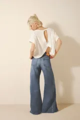 Jean corte oxford amplio de tiro medio, con cintura y cadera ajustada y piernas que se ensanchan desde la cadera hacia los tobillos con recortes en los laterales que le da un vuelo mayor a la pierna. Tejido rígido azul con lavado stone, localizado y bigotes. Con cierre y botón.