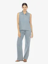 Musculosa de denim celeste, con cuello polo, escote en V con botones, sin mangas, de fit amplio y terminación desflecada.