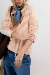 Remera de tejido de punto a rayas horizontales color naranja y blanco, de corte recto, cuello redondo y mangas largas.