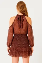 Vestido corto color marrón con estampado geométrico, cuello alto, hombros descubiertos y mangas largas abullonadas.