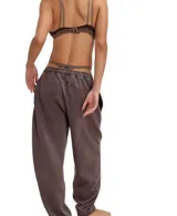 Pantalón de jogging negro con efecto gastado (acid wash), tiro medio y silueta relajada con puños ajustados en los tobillos. Presenta cordón de ajuste en la cintura y costuras visibles en contraste.