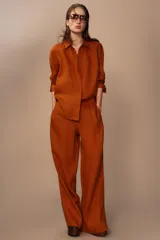 Pantalón palazzo color ladrillo, confeccionado en lino 100%, de tiro medio, cintura ajustable con cordones, bolsillos laterales ocultos y pierna ancha.