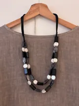 Collar de doble vuelta con cuentas de acrílico en color negro, blanco y gris, con cordón de gamuza negro ajustable.