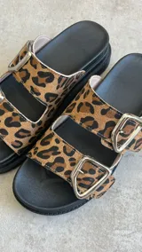 Sandalias con estampado animal print, dos tiras con hebillas plateadas y plataforma baja.