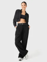 Blusa negra corta de manga larga con cuello camisero, cierre frontal con botones y dos bolsillos con fuelle en el pecho.
