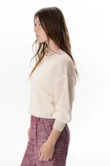 Sweater beige de tejido fino y mangas largas.
