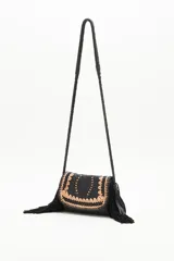 Cartera bandolera negra de cuero con diseño trenzado en el frente y flecos en gamuza. Tiene correa trenzada con terminación y forro de algodón.