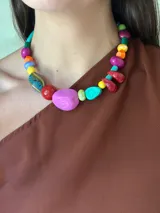 Collar corto con cuentas irregulares de diversos colores y texturas, incluyendo piezas de cerámica vidriada azul, resina rosa brillante, cuentas amarillas, rojas, turquesas y verdes.