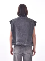 Chaleco de denim azul lavado, sin mangas, con cuello camisero, botones frontales y bolsillos de parche en el pecho.