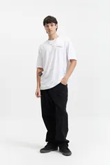 Remera blanca de manga corta con estampado en la espalda con texto en gris y diseño floral.