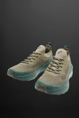 Zapatilla deportiva color arena con detalles en verde y suela azul. Fabricada en tejido de punto transpirable con puntera y talón recubiertos de material Shield Protect Max. Cuenta con ajuste mediante cordones, tirador trasero, plantilla OrthoLite® extraíble, entresuela Spume Foam V2 y suela de goma.