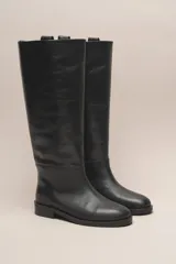 Bota alta de cuero color marrón, con caña recta y suela plana.