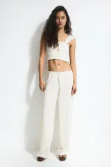 Pantalón recto color crema, de tejido arrugado suave, con cintura elástica y cordón ajustable.