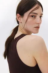 Musculosa marrón de punto de algodón acanalado, corte entallado, cuello redondo y ribete fino en escote y sisas.