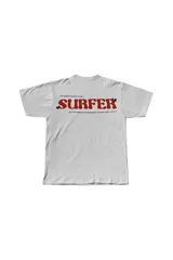 Remera blanca de algodón con cuello redondo y estampado pequeño en el pecho con la palabra "SURFER" en rojo.
