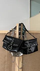 Cartera negra con textura símil cocodrilo, con herrajes plateados y cadena decorativa.