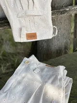 Pantalón de lino color beige con estampado de pequeñas flores blancas y rojas.