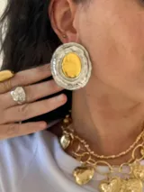 Par de aros grandes ovalados plateados con centro dorado y diseño irregular.