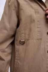 Cazadora color beige con cuello clásico, cierre frontal con botones, mangas largas y bolsillos de parche en el pecho.