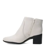 Botín de cuero color marrón, con caña baja, punta redonda y taco ancho y bajo. Presenta costuras visibles en el lateral y un pequeño detalle metálico en el cuello.