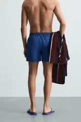 Short de baño azul con cintura elástica ajustable con cordón, bolsillos laterales y bolsillo trasero de plastrón.