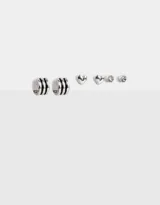 Set de aros plateados con diferentes diseños: aros tipo argolla con tres líneas horizontales, aros tipo botón con forma de corazón y aros tipo botón con strass.
