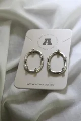 Aros colgantes plateados con forma ovalada irregular y apliques de strass.