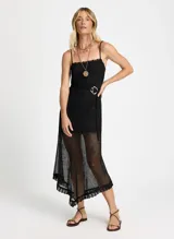 Vestido midi negro de lurex con breteles finos, corte ajustado y falda asimétrica con volados. Incluye cinturón de soga con hebilla dorada.