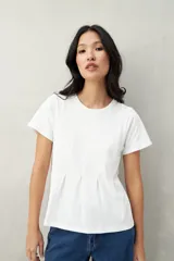 Remera blanca de algodón con cuello redondo y costuras verticales en el frente.