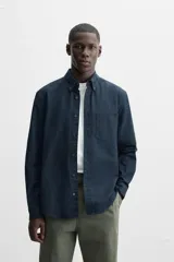 Camisa azul marino de corte regular fit, confeccionada en tejido de algodón Oxford. Tiene cuello abotonado, manga larga con puños abotonados, bolsillo de parche en el pecho y cierre frontal con botones.