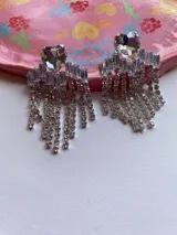 Par de aros colgantes con forma de corazón de cristal y flecos de strass plateados.