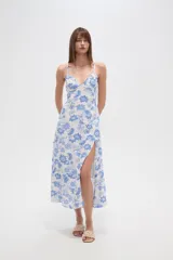 Vestido largo confeccionado en viscosa con estampado floral azul sobre fondo blanco. Posee escote en V, tirantes finos, cintura elástica y una abertura lateral profunda en la falda.