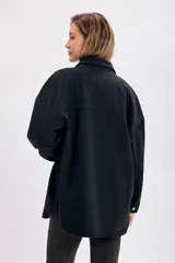 Sobrecamisa de jean negro con cuello clásico, cierre frontal con botones a presión, dos bolsillos con solapa en el pecho y corte holgado.