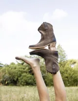Botas cortas negras de cuero con bordados blancos estilo cowboy.