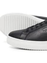 Championes negros de cuero sintético con suela blanca de goma y cordones negros.
