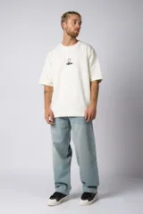 Remera color crudo de corte oversize con estampado pequeño en el centro del pecho.
