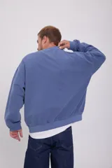 Buzo azul de manga larga y cuello redondo, con calce oversize y logo estampado en el pecho.