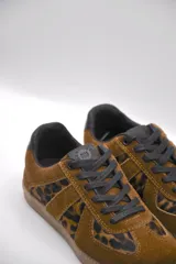 Zapatillas urbanas de cuero color crema con puntera y talón en gamuza gris, suela de goma marrón y cordones grises.