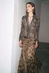 Falda midi de tiro alto con estampado paisley en tonos marrones y dorados. Presenta cintura con drapeado lateral y bajo asimétrico evasé. Cierre con cremallera oculta en la costura.